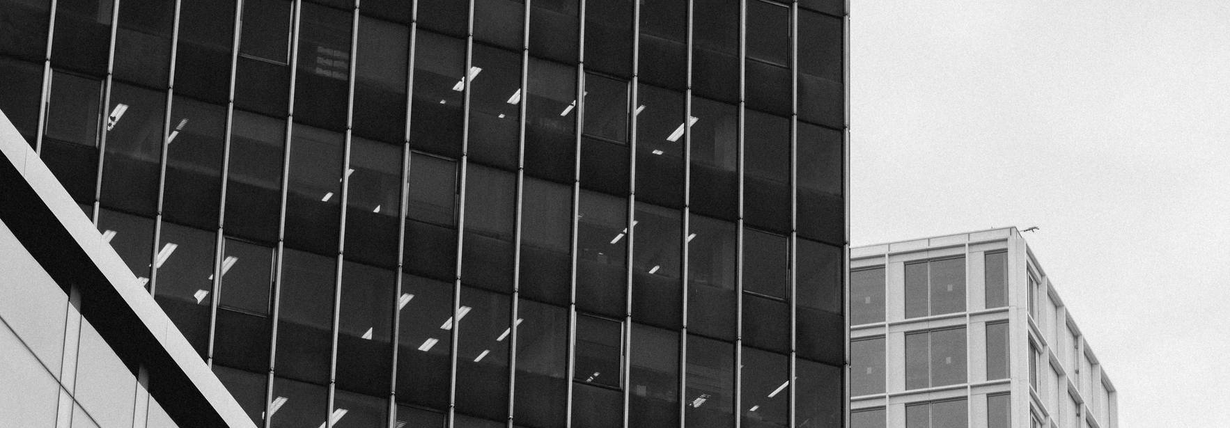 Edificios modernos reflejados en un entorno urbano en blanco y negro.