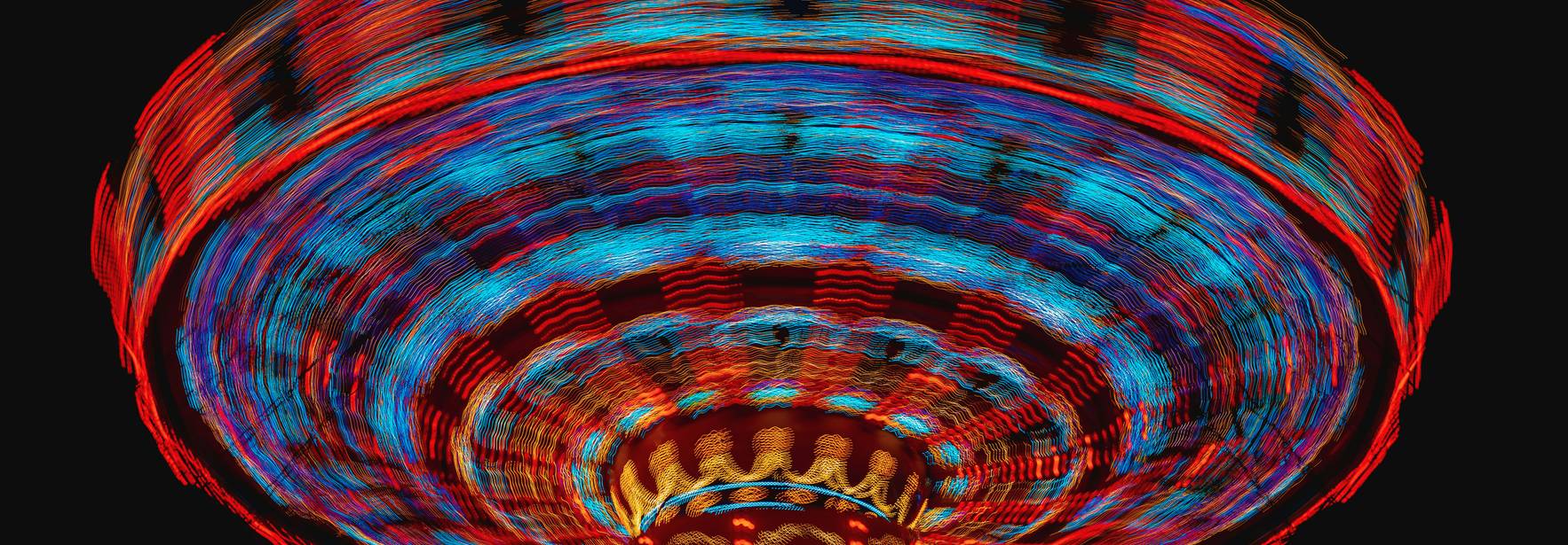 Una atracción de feria iluminada girando en la oscuridad.