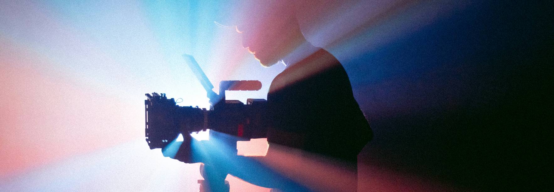 Silhouette de una persona sosteniendo una cámara en medio de luces de colores.