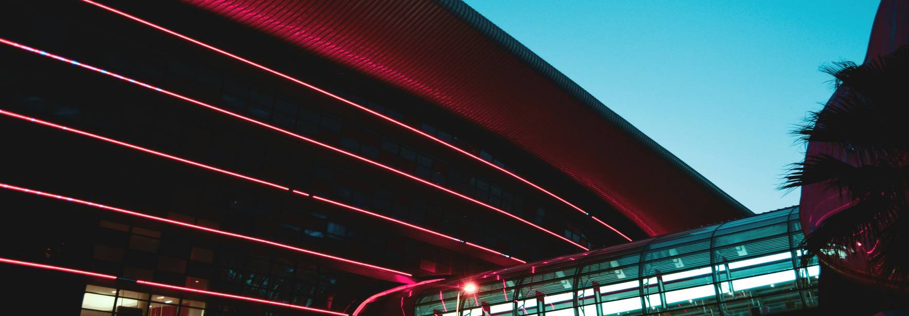 Una moderna edificación iluminada con luces de neón en un cielo al atardecer.