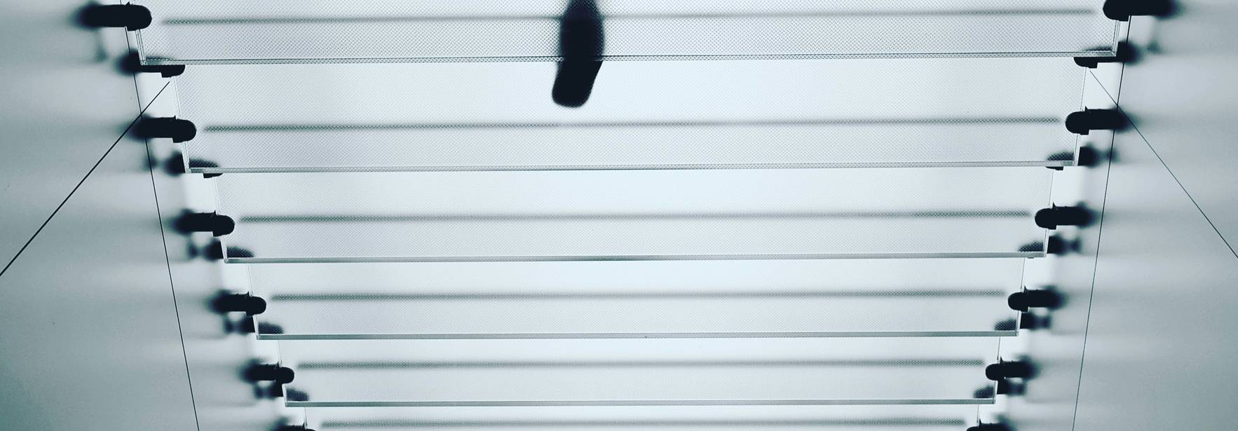Una figura humana camina sobre una estructura lineal en un entorno minimalista.
