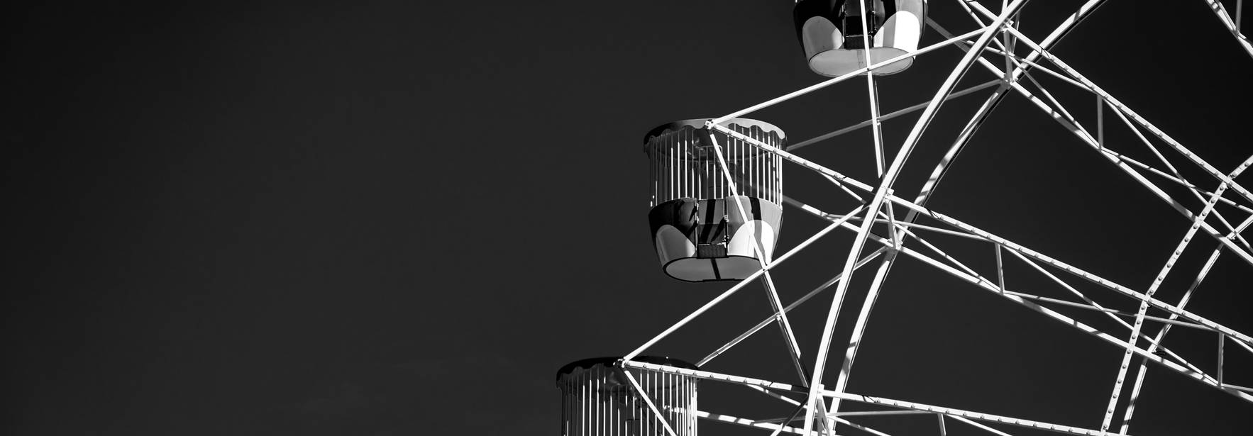 Una noria en blanco y negro que muestra sus cabinas y estructura.