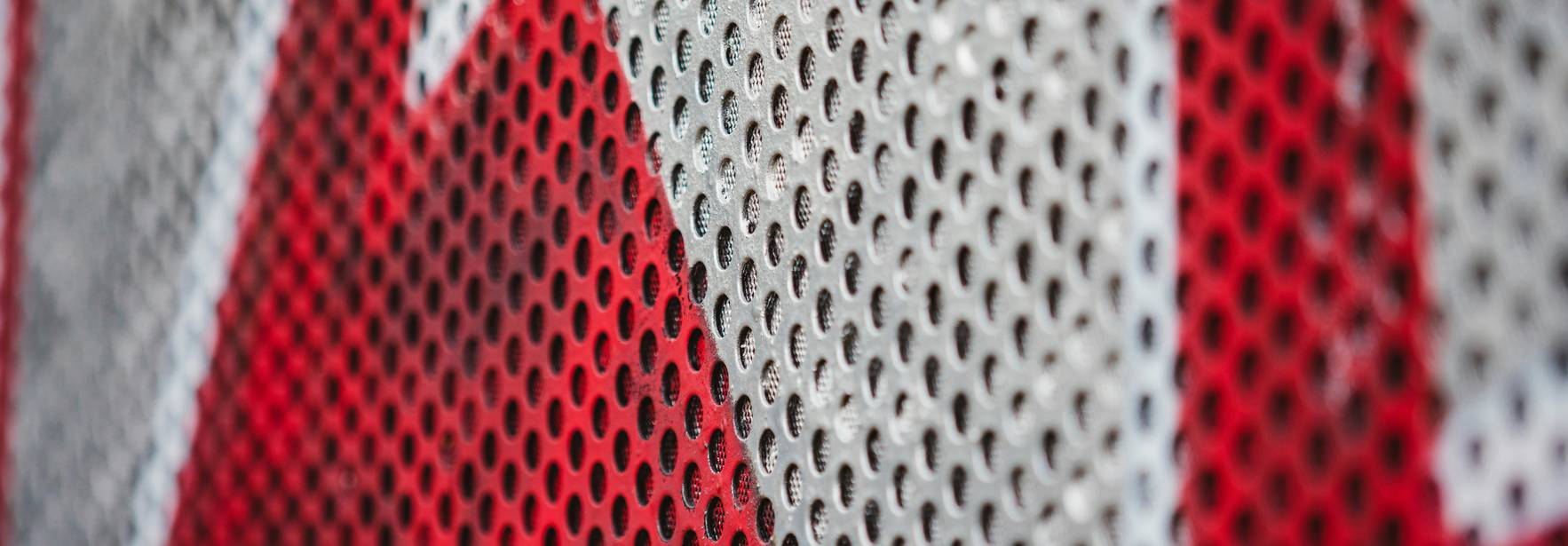 Una superficie de metal perforado con un patrón en rojo y blanco.