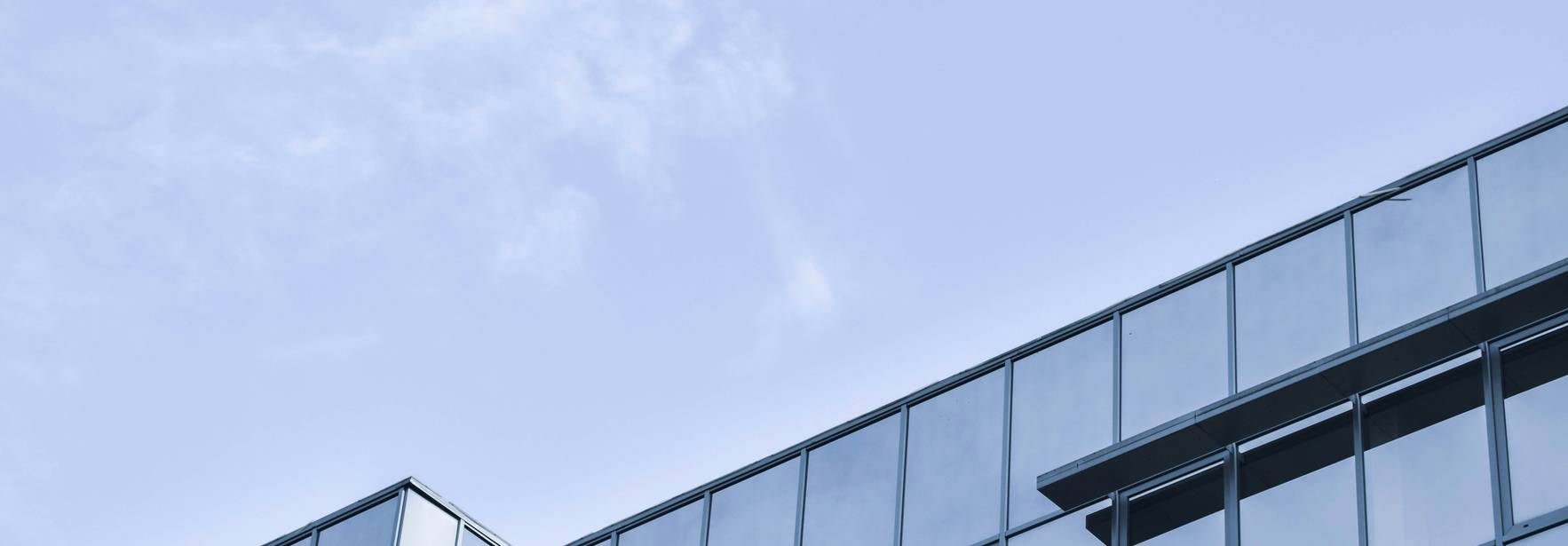 Una imagen de un edificio moderno con fachadas de vidrio y un cielo azul claro.