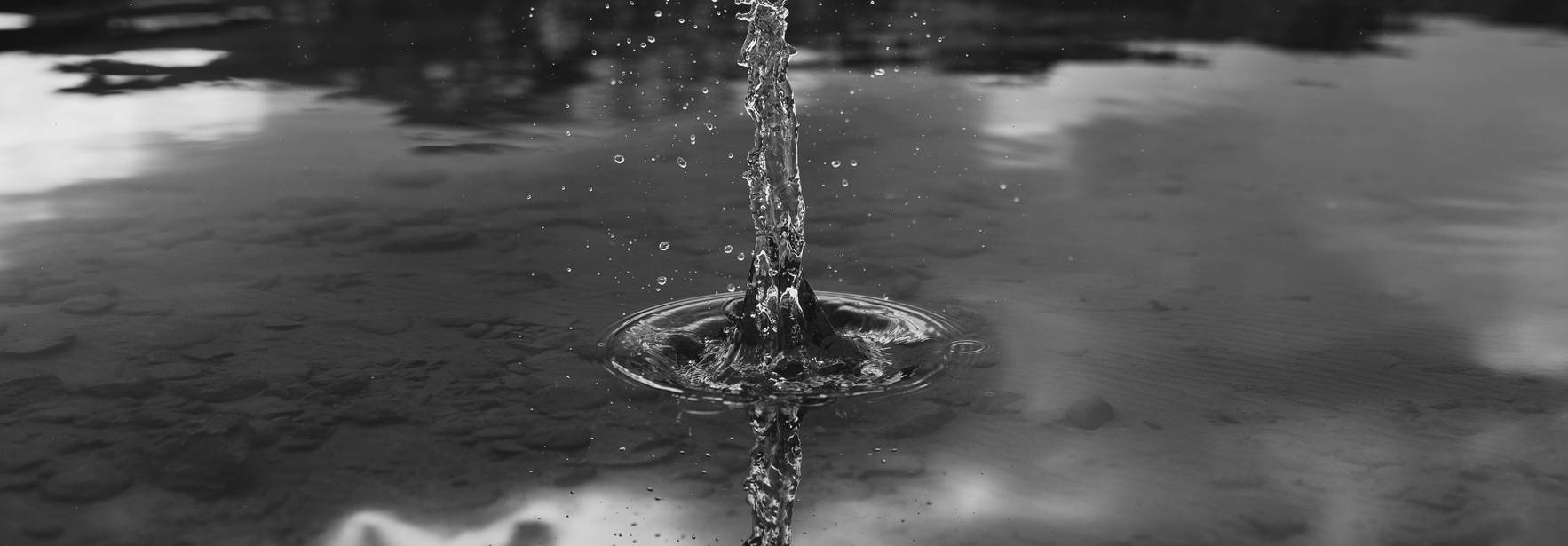 Una columna de agua salpica y se eleva desde la superficie de un lago en un entorno natural.