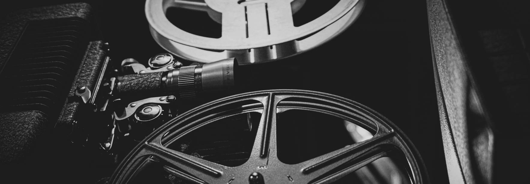 La imagen muestra bobinas de película cinematográfica en blanco y negro.