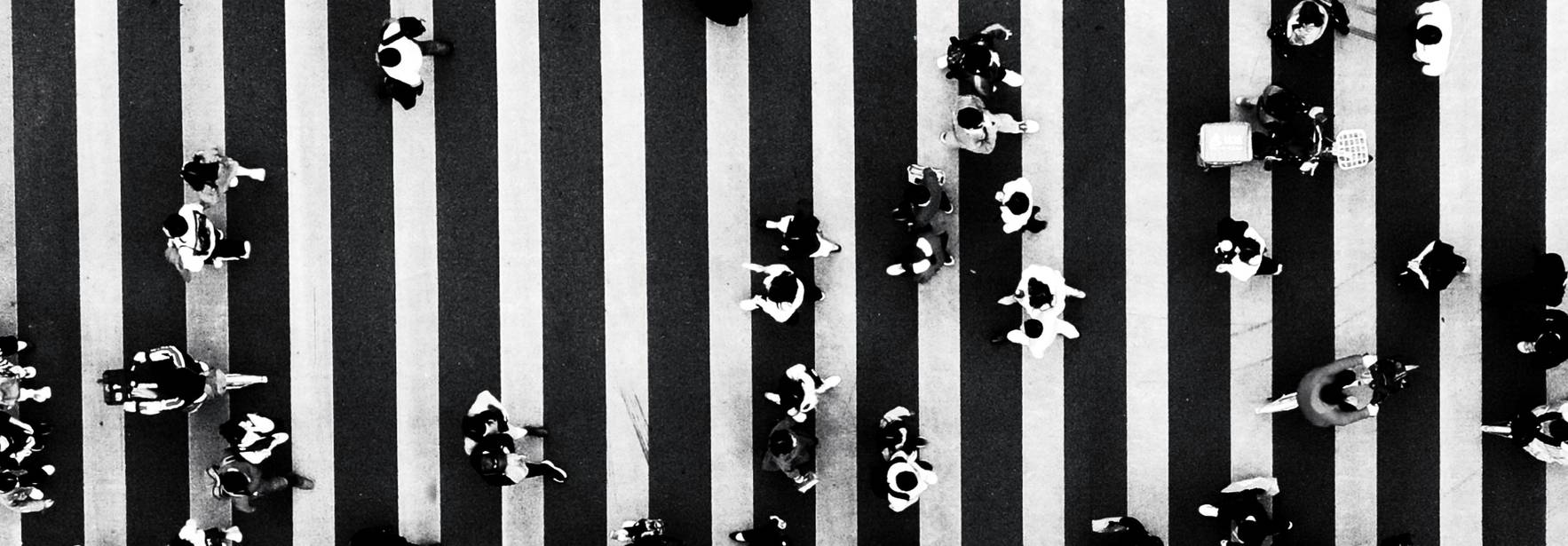 Una vista aérea de personas cruzando un paso de peatones en blanco y negro.