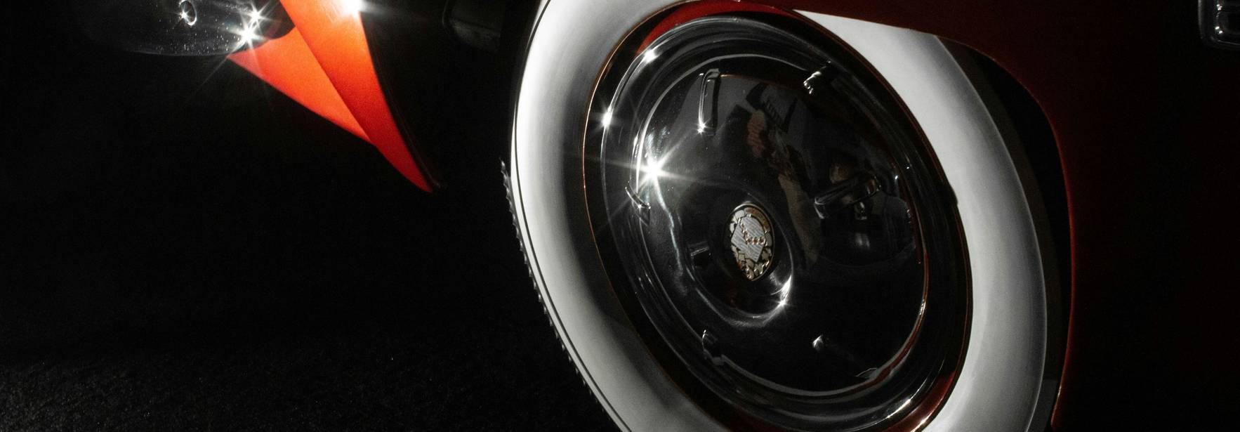 Un close-up de una rueda brillante de un automóvil clásico con llanta blanca.