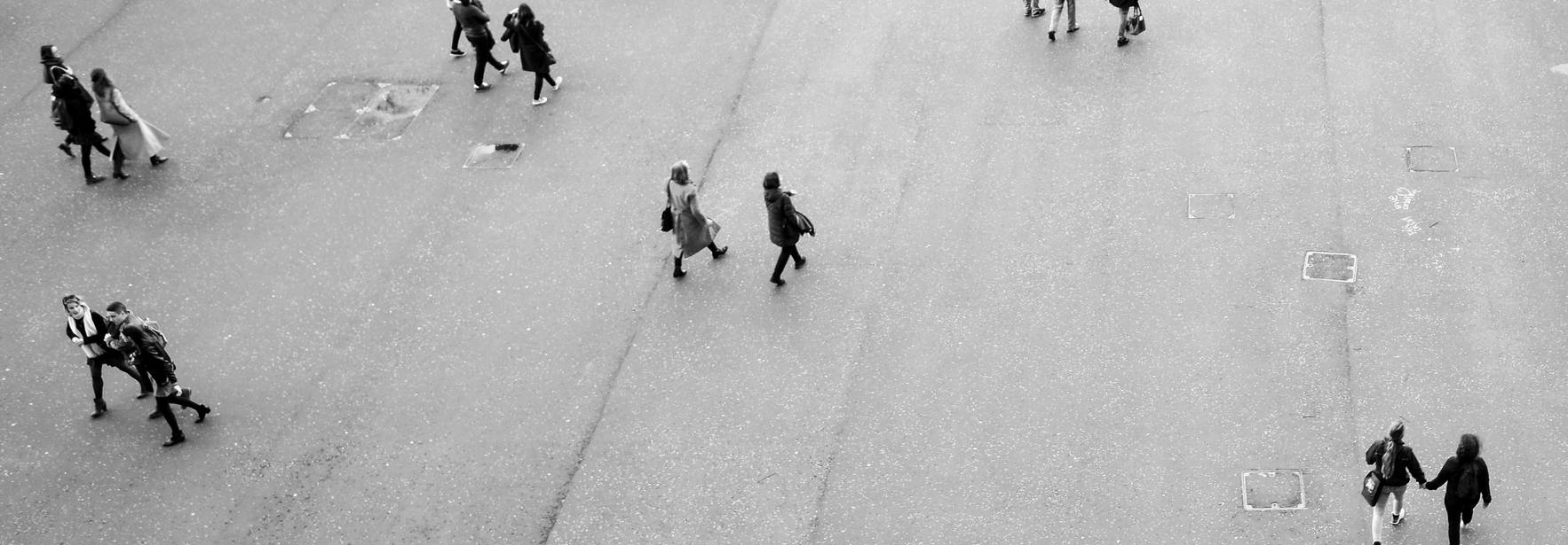 Una multitud de personas camina sobre una superficie pavimentada en una imagen en blanco y negro.