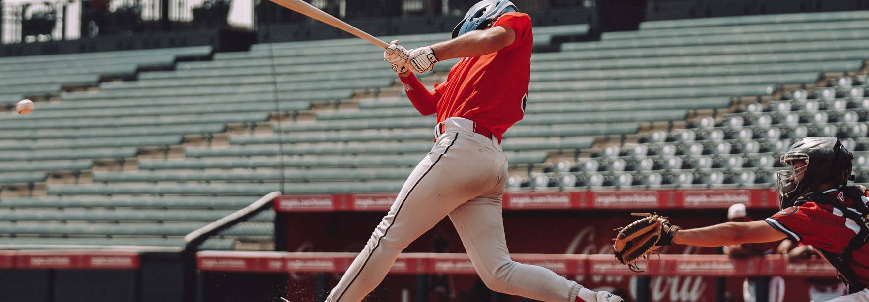 Un jugador de béisbol está a punto de golpear la pelota con un bate en un campo vacío.