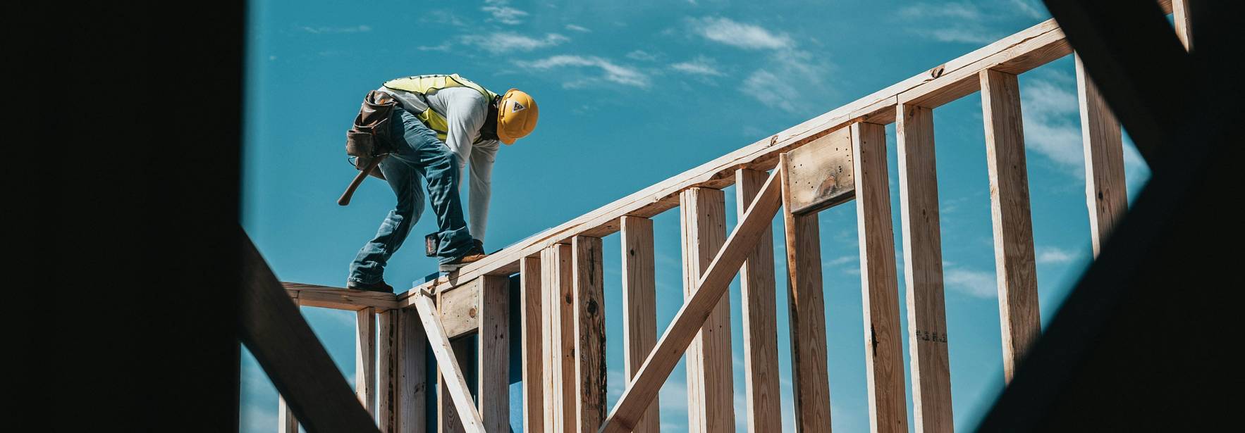 Un trabajador de la construcción está trabajando en una estructura de madera bajo un cielo claro.