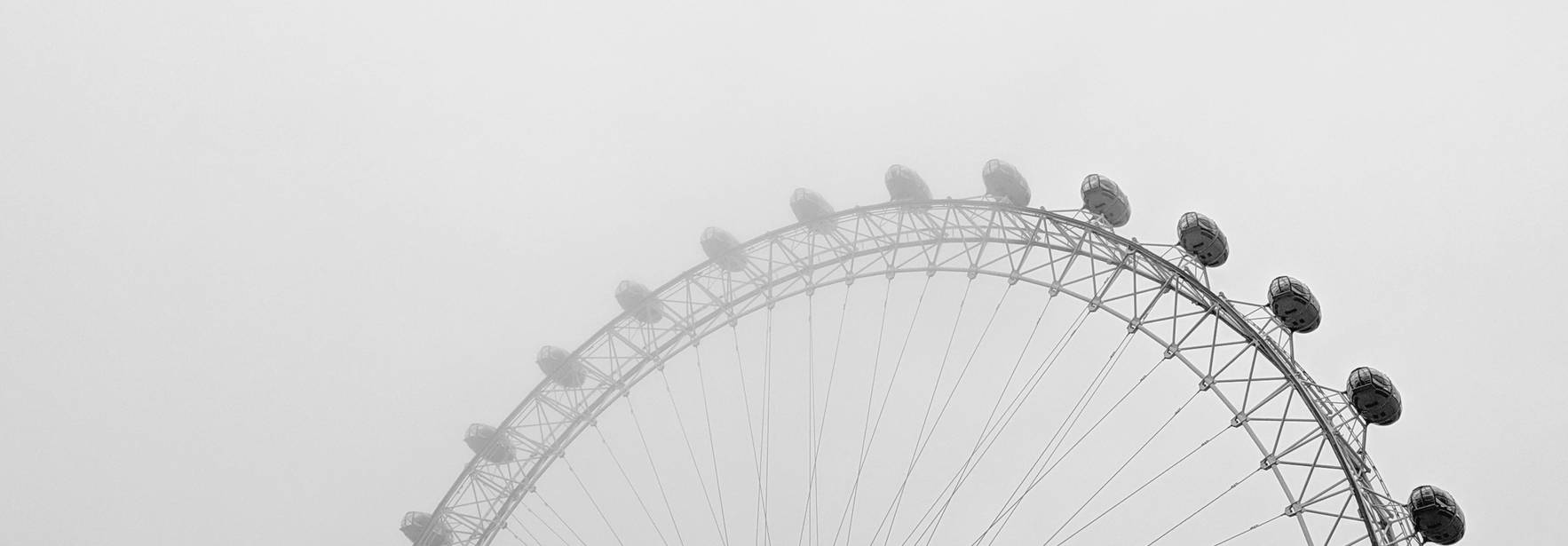 Una noria blanca parcialmente visible en un día nublado y neblinoso.