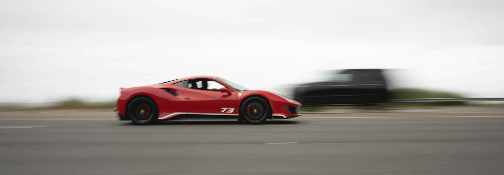 Un coche deportivo rojo se desplaza a gran velocidad en la carretera.