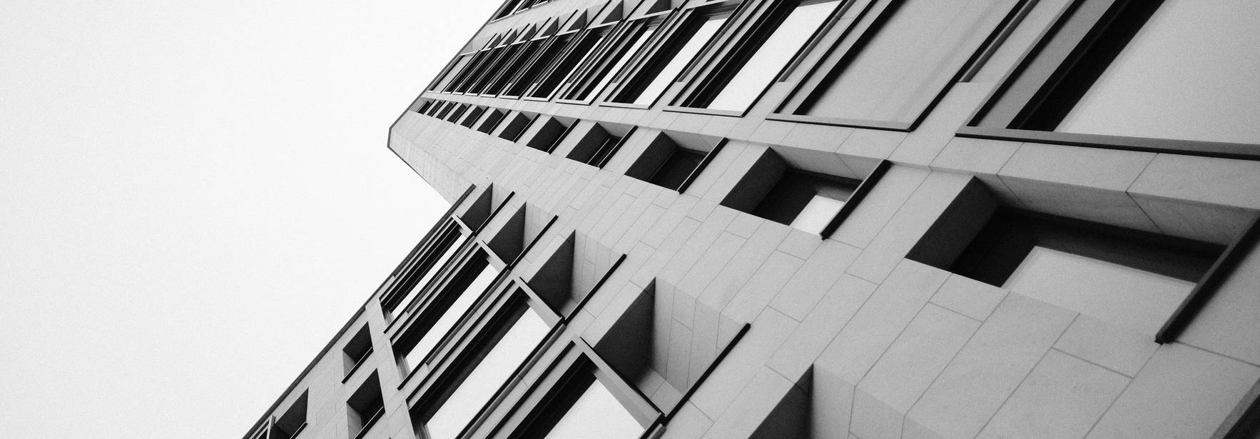 Una vista en ángulo ascendente de un edificio moderno en blanco y negro.