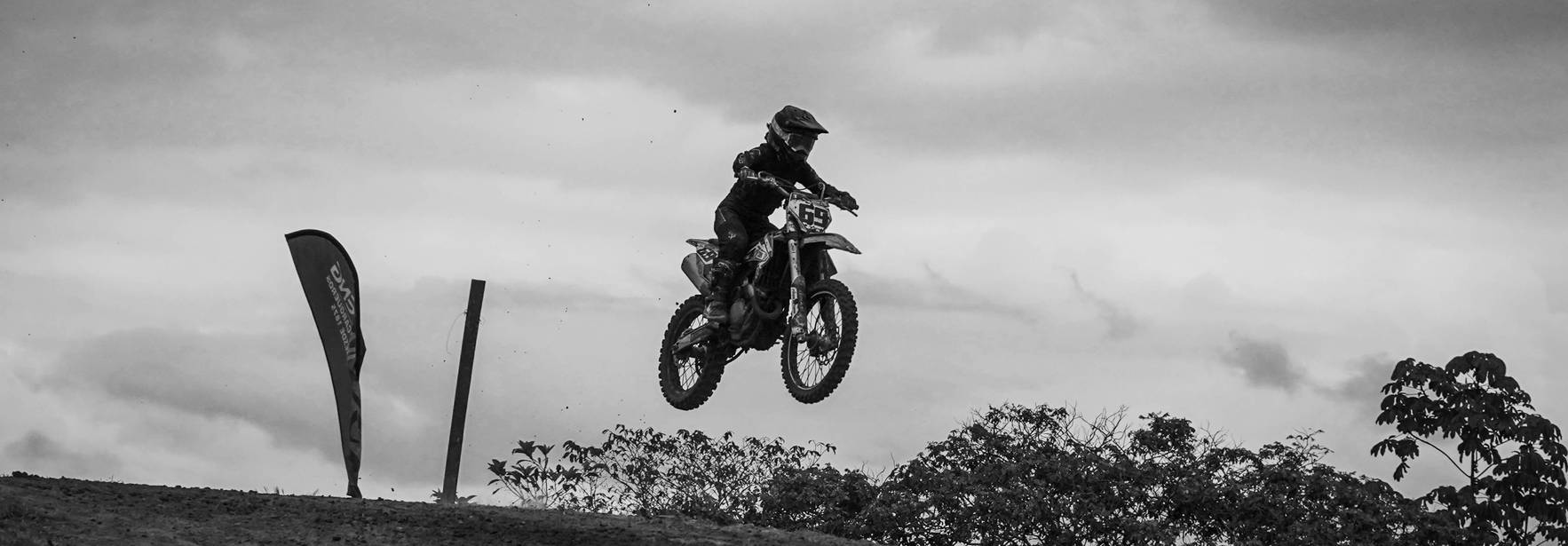Un motociclista realiza un salto en una pista de motocross en un entorno natural.