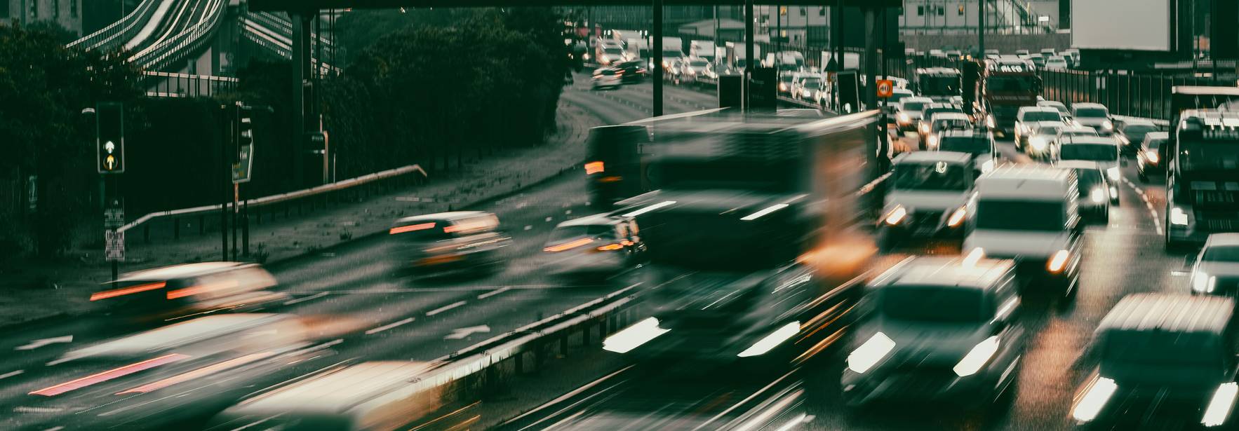 Una vista de tráfico en una carretera urbana con vehículos en movimiento y señales visibles.