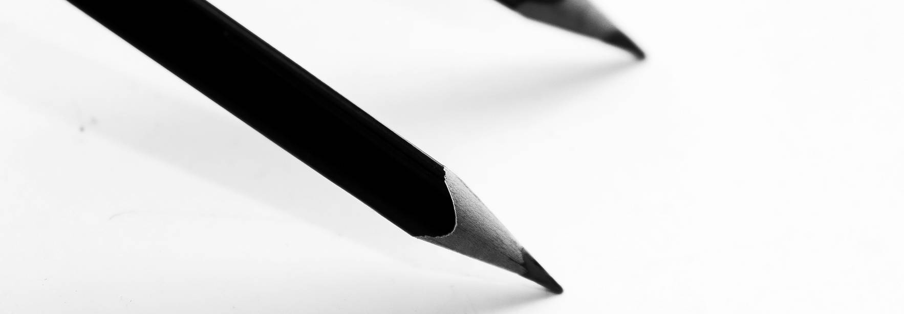 Dos lápices negros sobre un fondo blanco.