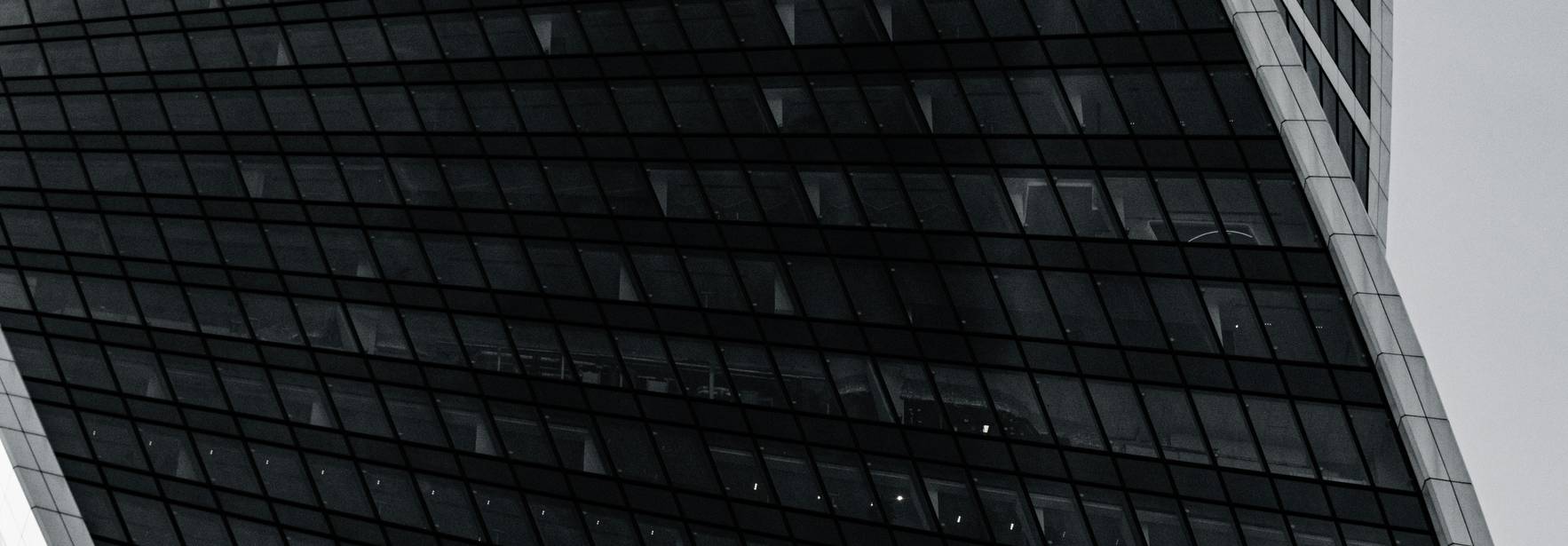 Una moderna fachada de edificio con un diseño curvado y líneas elegantes en tonos oscuros.