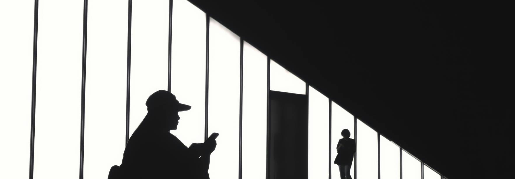 Siluetas de personas en un espacio arquitectónico iluminado por grandes ventanales.