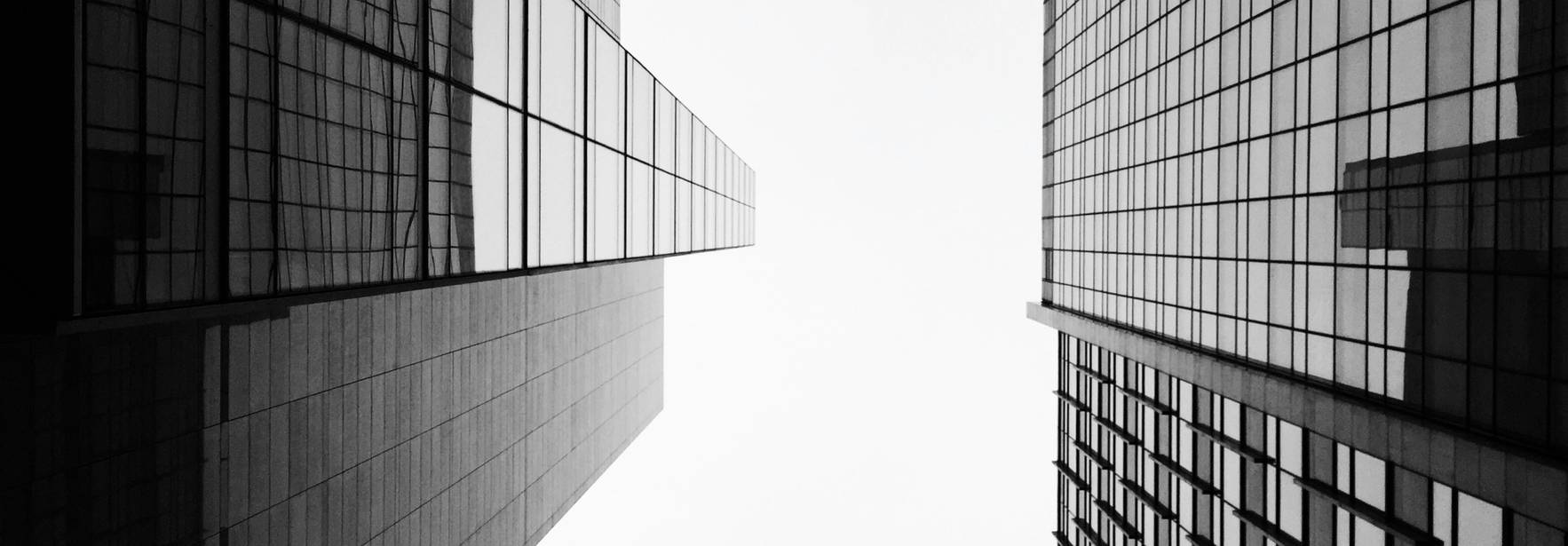 La imagen muestra la vista hacia arriba entre dos edificios altos con fachadas de vidrio.