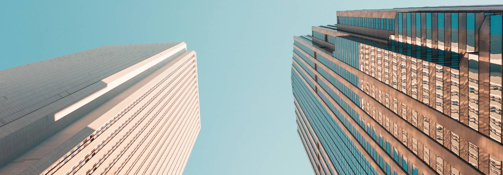 La imagen muestra una vista angular de edificios altos bajo un cielo despejado.