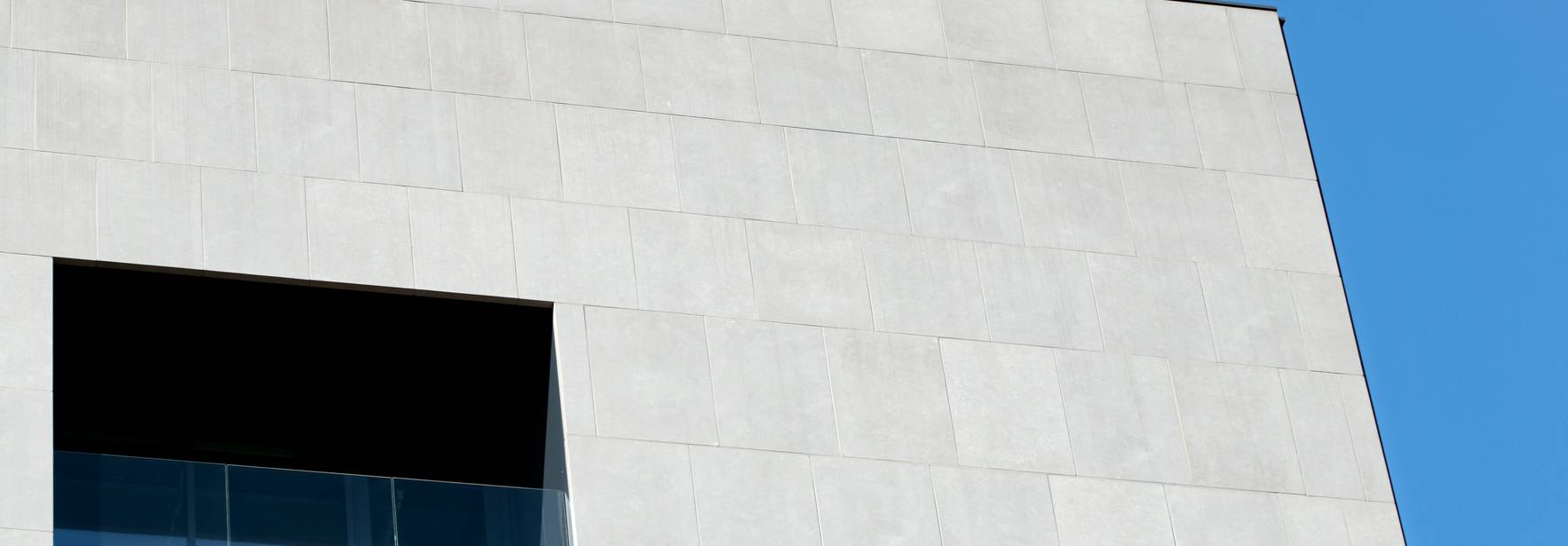 Un edificio moderno con una fachada blanca y un ventanal en la parte superior.