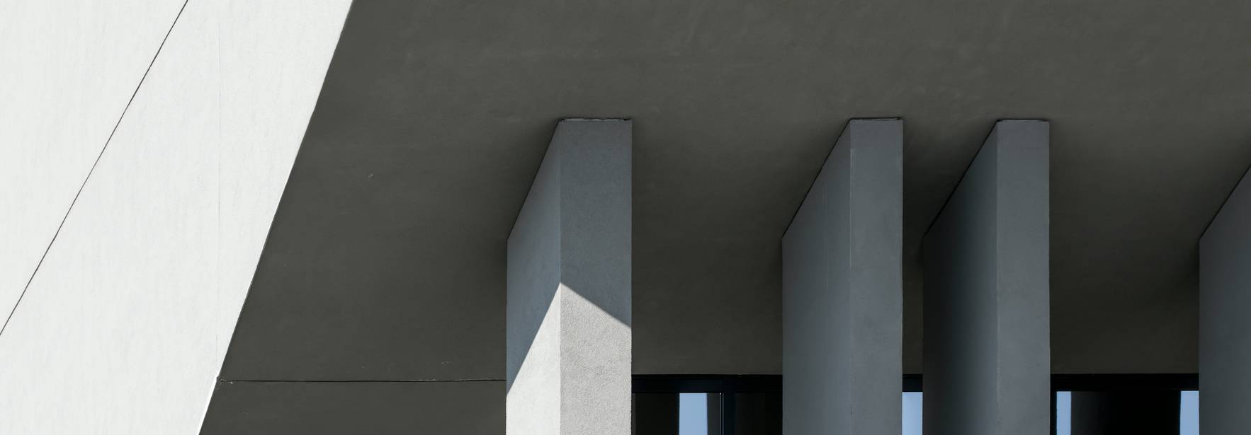 La imagen muestra una estructura arquitectónica moderna con líneas geométricas y sombras marcadas.
