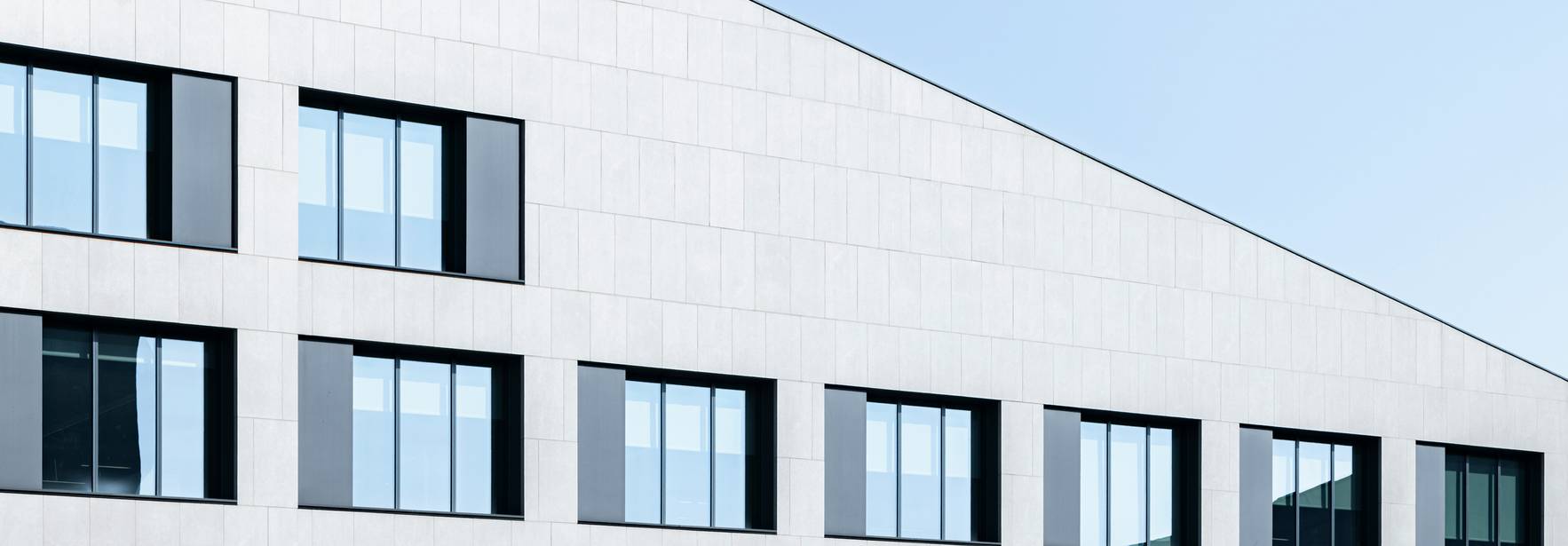 Edificio moderno con una fachada asimétrica y ventanas lineales.