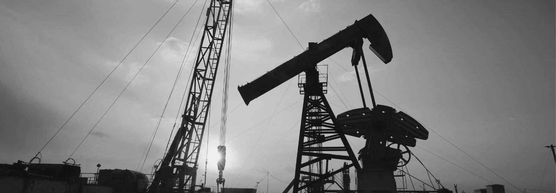 Una plataforma de extracción de petróleo al atardecer, destacando las estructuras metálicas en silueta.