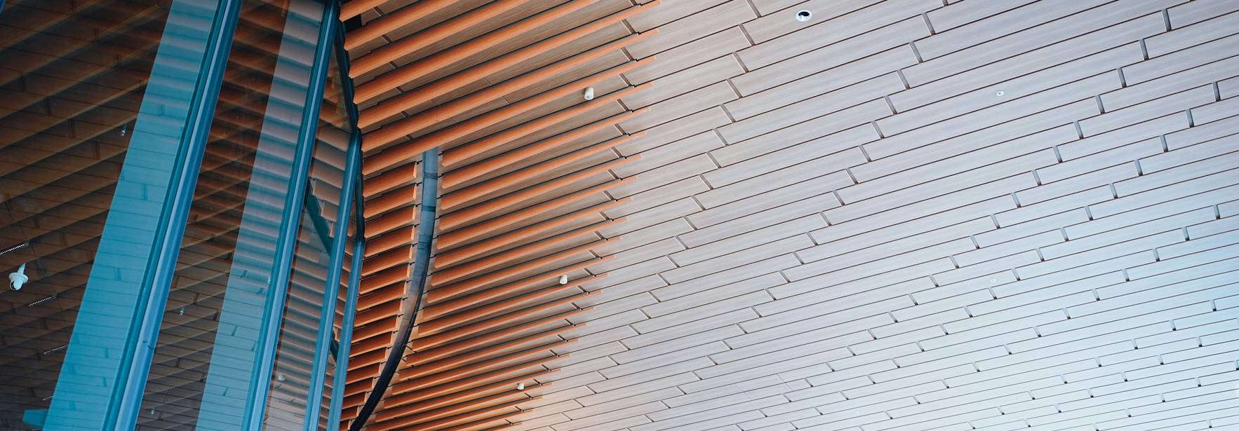 La imagen muestra un techo arquitectónico con un diseño de paneles de madera que se curvan hacia arriba.