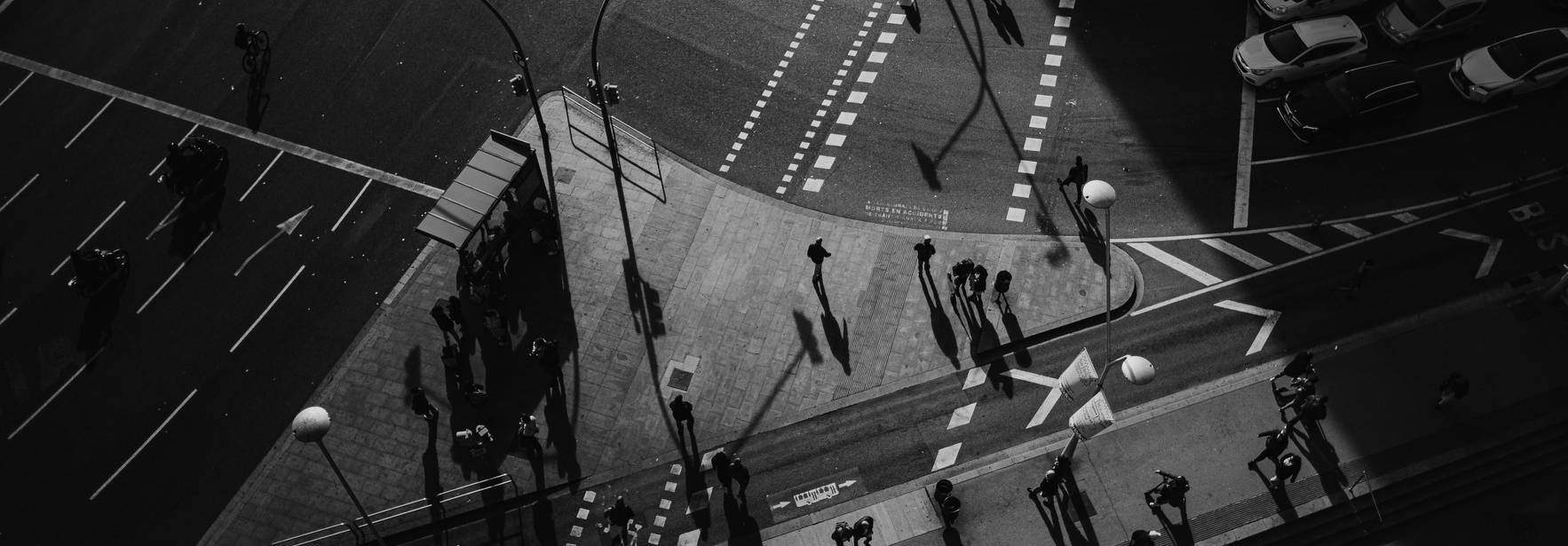 Una vista aérea de una intersección urbana con personas y sombras marcadas.