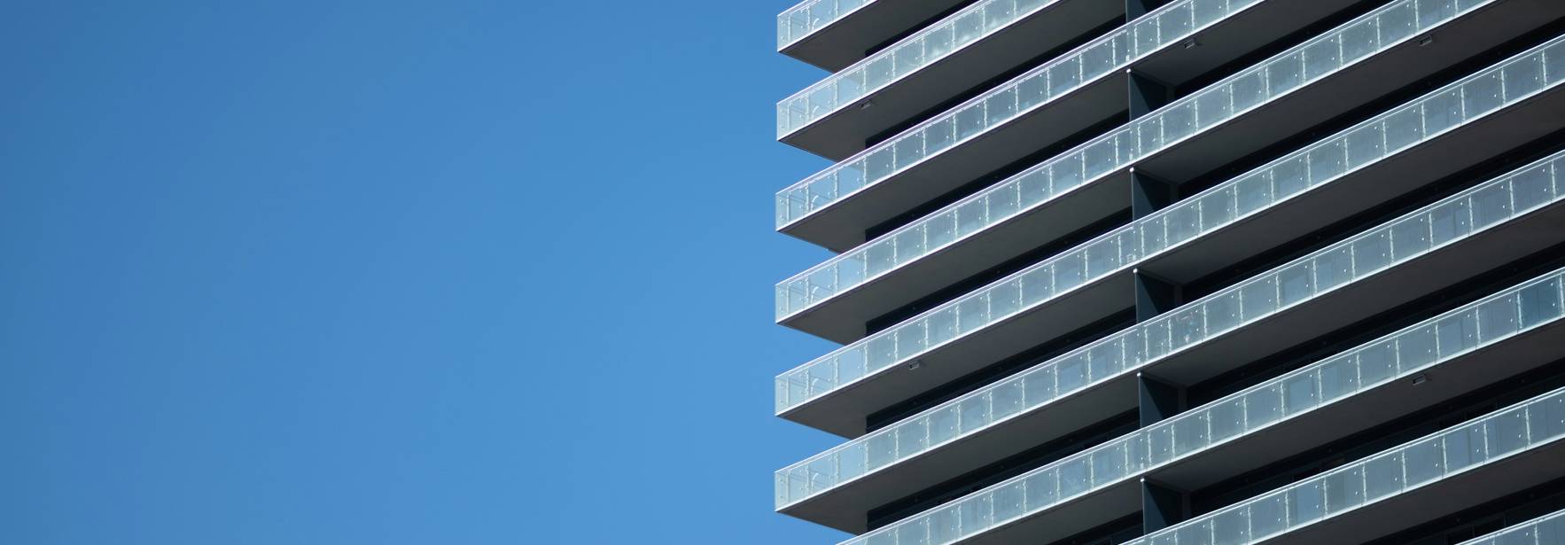 Una imagen de un edificio moderno con balcones en un día despejado.