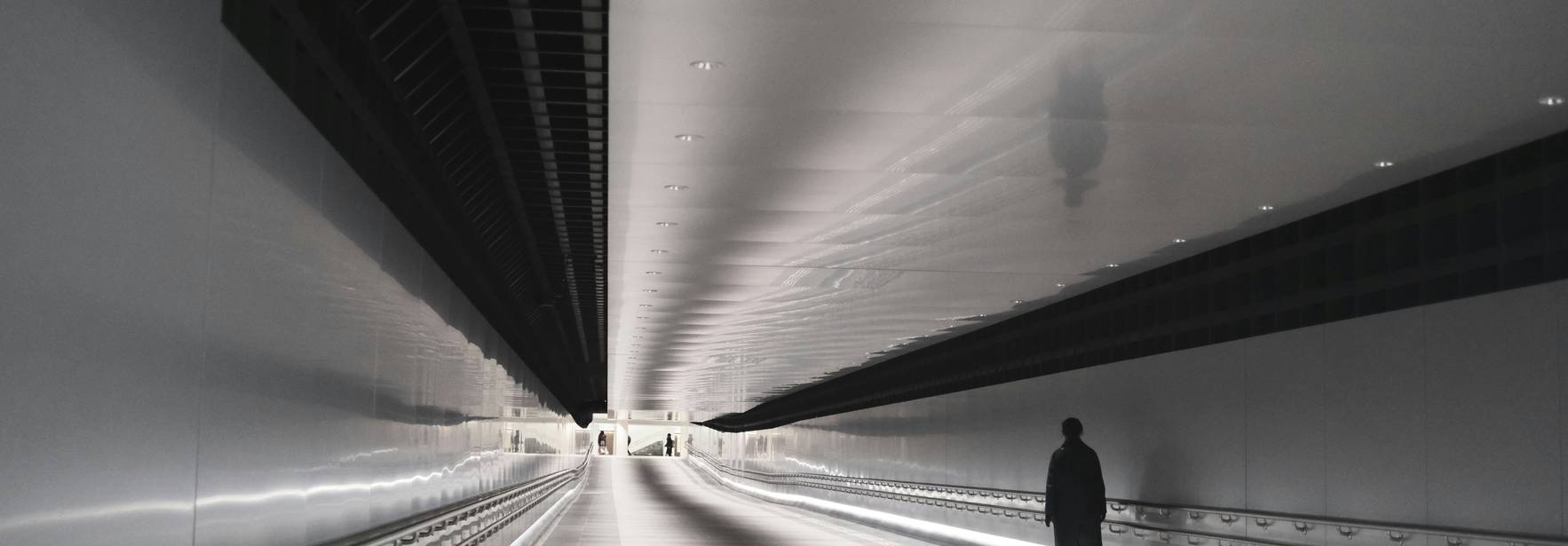 Un pasillo amplio y moderno con un único caminante al final.