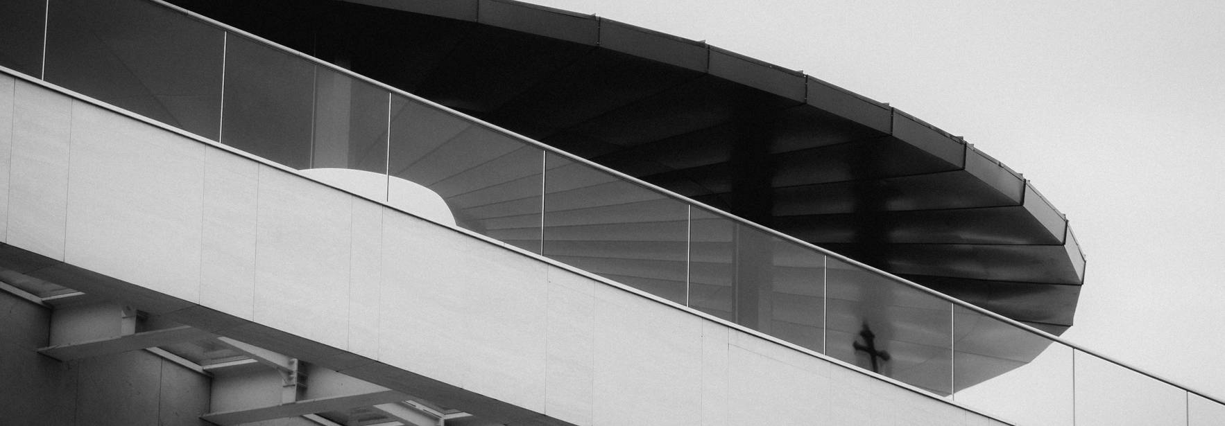 La imagen muestra una estructura arquitectónica moderna con un diseño curvilíneo en un entorno minimalista.