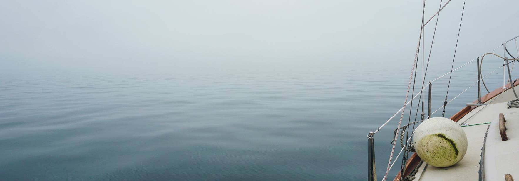 Una embarcación en medio de un mar tranquilo envuelto en niebla.