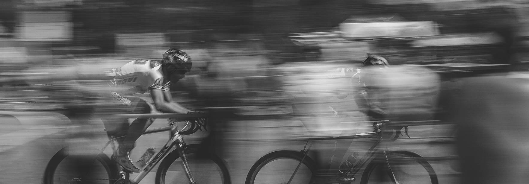 Ciclistas compitiendo en una carrera con un efecto de movimiento en blanco y negro.