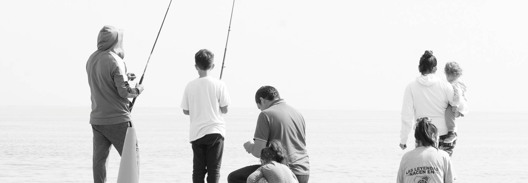 Un grupo de personas pesca en la playa frente al mar.