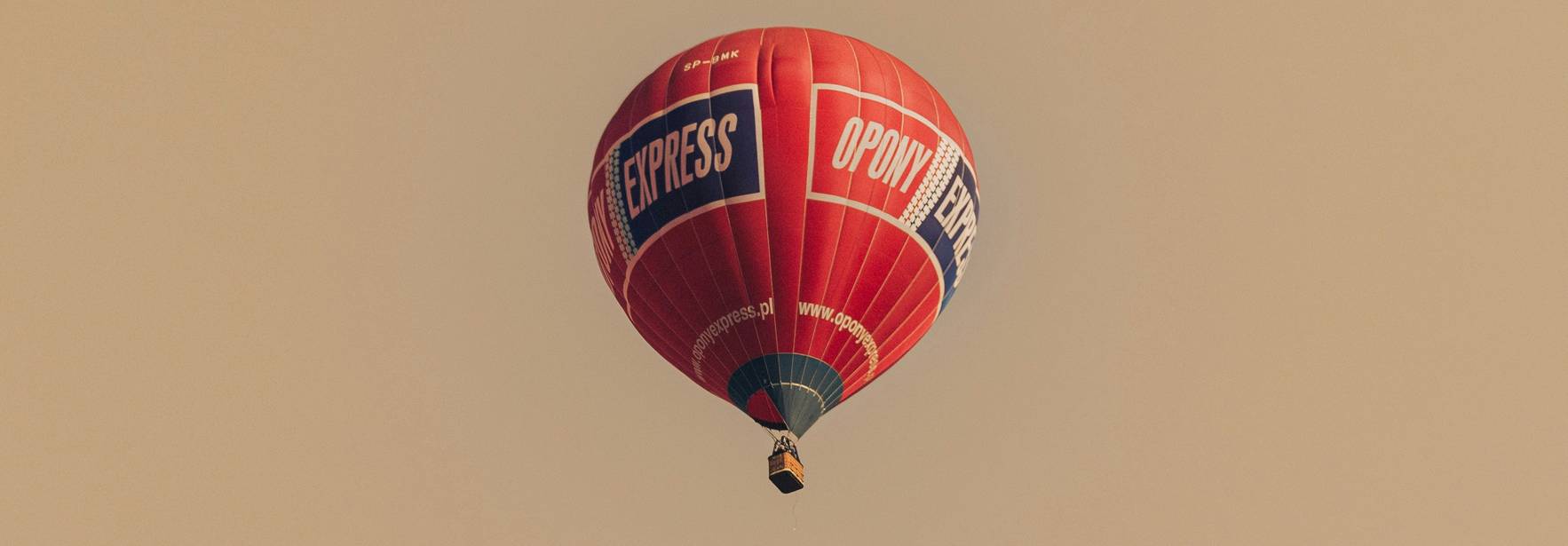 Un globo aerostático de color rojo se eleva en el cielo.