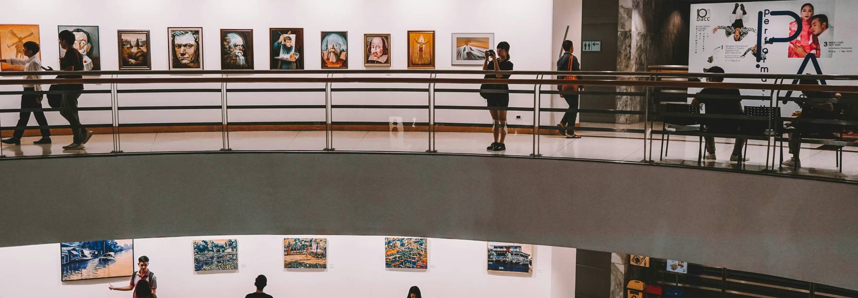 Una vista de un museo o galería de arte con varias personas observando las obras en las paredes.