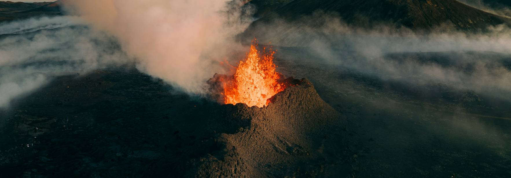 Un volcán en erupción con lava y humo en un paisaje árido.