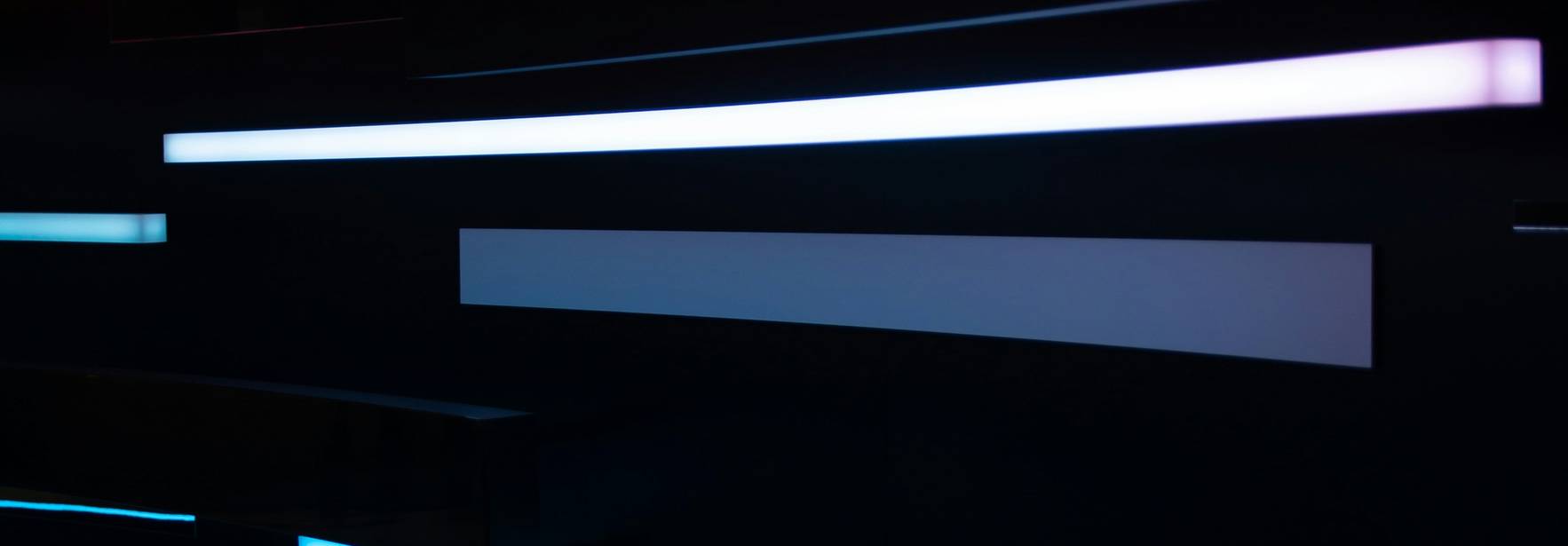 La imagen muestra una serie de líneas de luz en tonos brillantes que parecen moverse en la oscuridad.