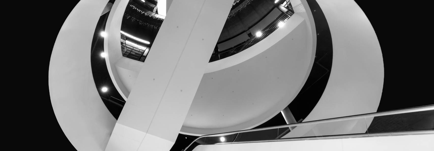 La imagen muestra una estructura arquitectónica circular y moderna vista desde abajo, con elementos en blanco y negro.