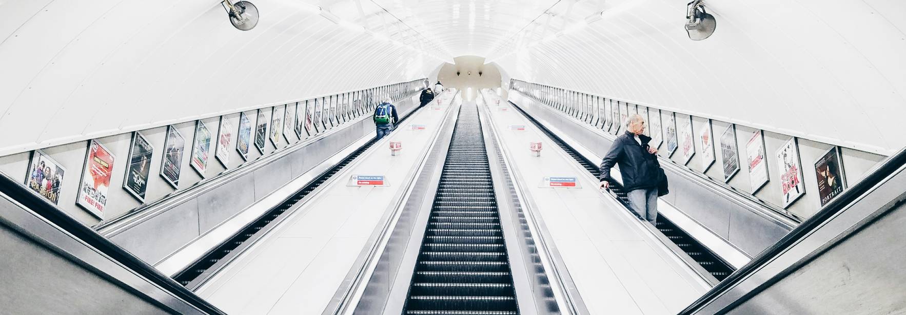 Una vista de una escalera mecánica en una estación de metro con personas subiendo y bajando.