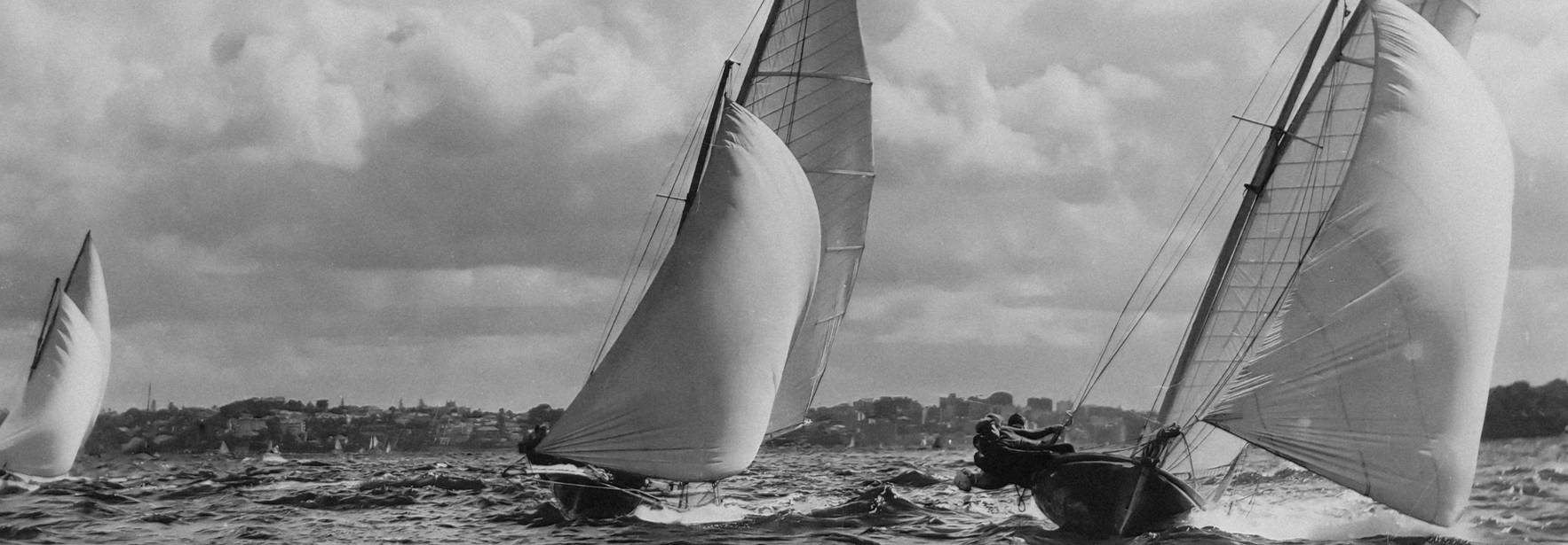 Una imagen en blanco y negro de veleros navegando en el mar bajo un cielo nublado.