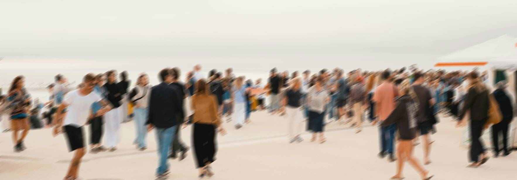 Una multitud de personas caminando en una playa con un ambiente desenfocado.