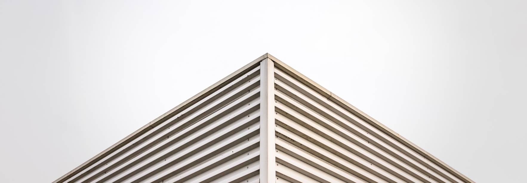 Una esquina de un edificio moderno con líneas rectas y un diseño minimalista en tonos gris y rojo.