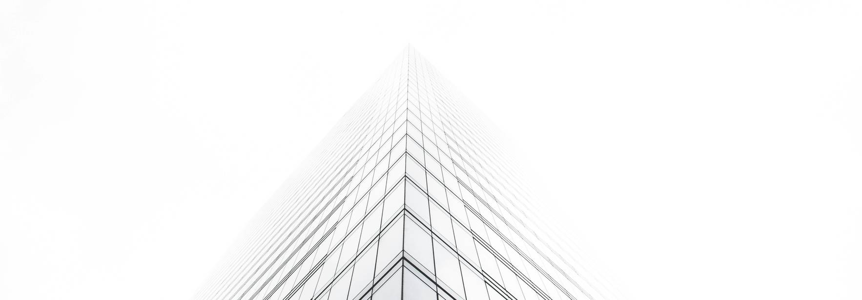 Un rascacielos se eleva en la niebla, con una perspectiva desde abajo que acentúa su altura.