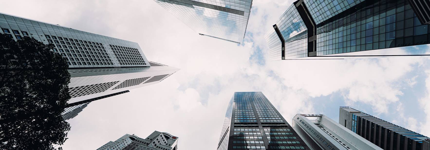 Vista hacia arriba de un grupo de edificios modernos y altos bajo un cielo nublado.