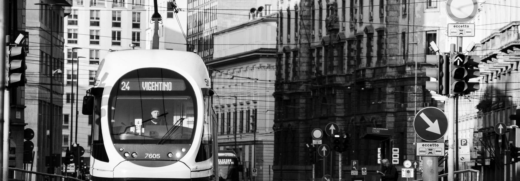 Un tranvía blanco y negro circula por una calle rodeada de edificios antiguos.