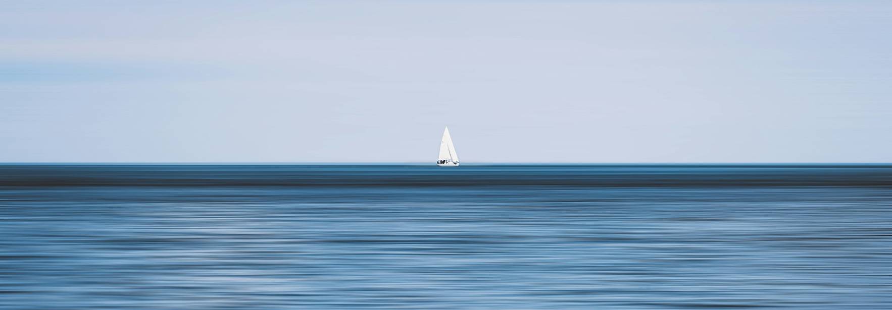 Una embarcación de vela se encuentra en un mar tranquilo bajo un cielo azul.